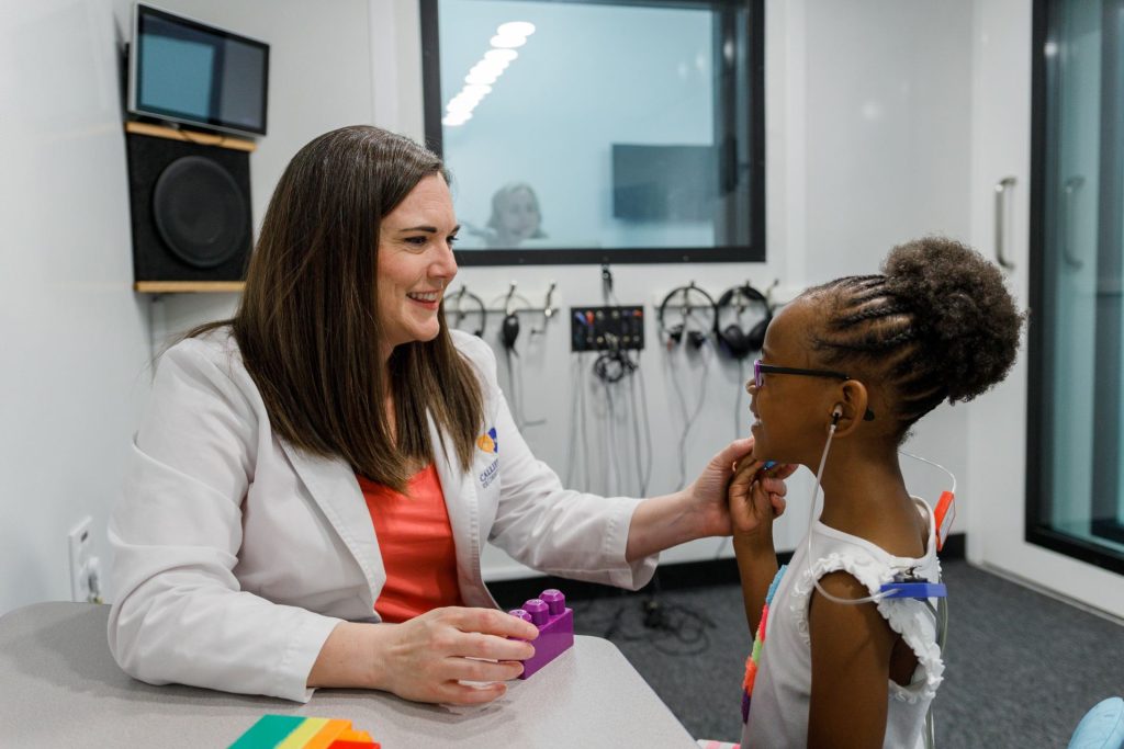 Audiologist Stephanie Williams testing the hearing of a young patient