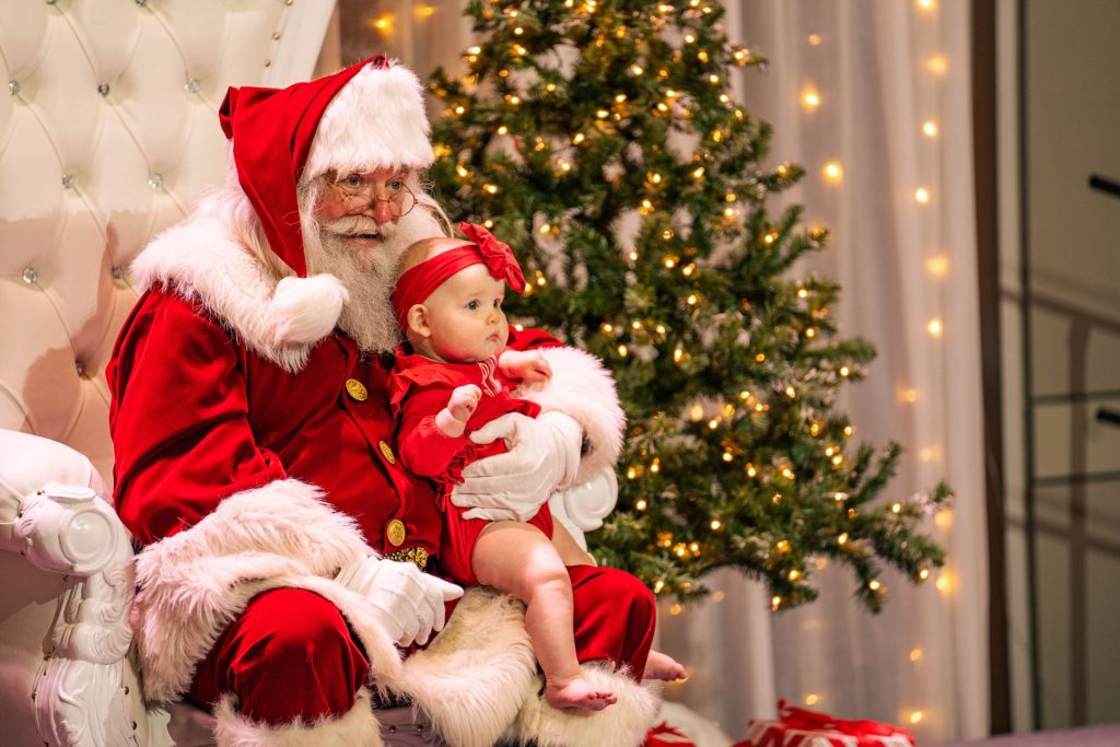 Santa Clause posing for a photo with a baby.