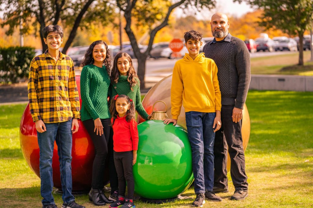 The Joshi family posing for a family portrait in front of a lawn ornament at the Davidson-Gundy Alumni Center.