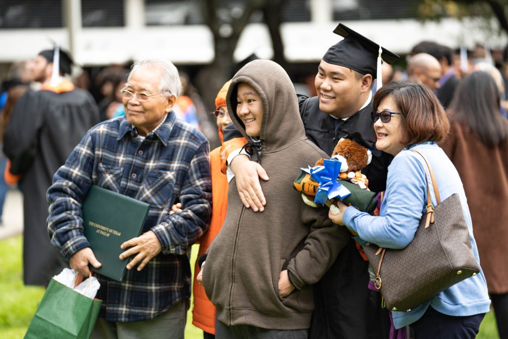 Family posing for a photo with new graduate during graduation ceremony.