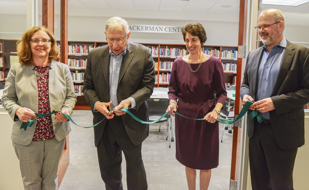 People cutting a ribbon during a naming of the Ackerman Center reference library.