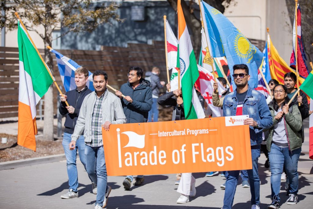 Students marching in the homecoming parade holding a banner that reads Parade of Flags.