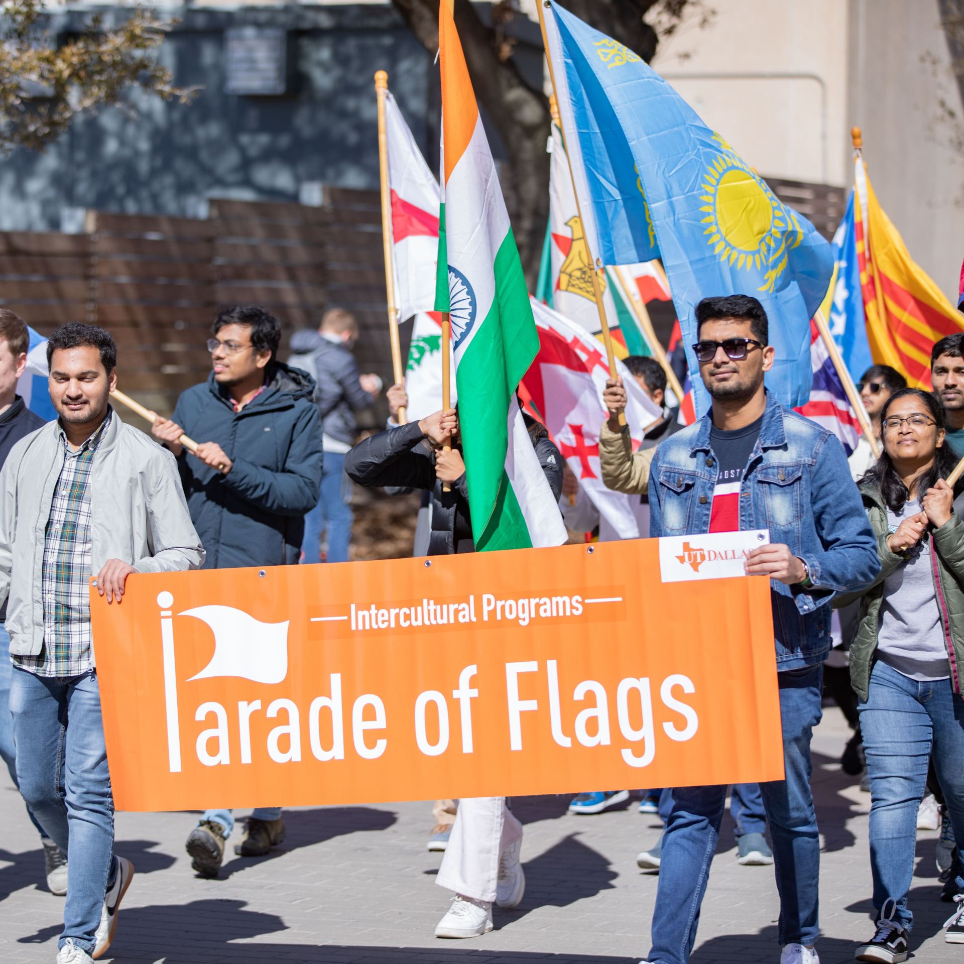 Photo Gallery: Homecoming 2023. Students marching in the homecoming parade holding a banner that reads Parade of Flags.