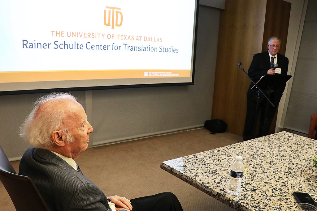 Dr. Rainer Schulte listening to Richard Kurjan speak at a podium during naming ceremony.