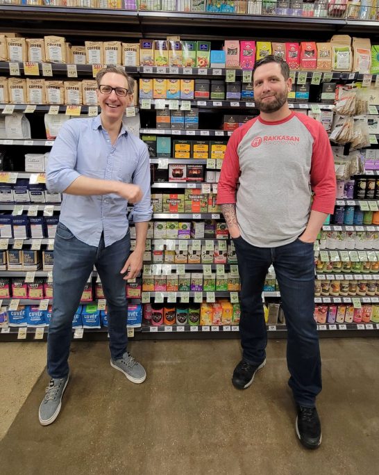 Brandon Friedman and Terrence Kamauf posing for a photo in front of their tea products for sale in a Dallas grocery store.
