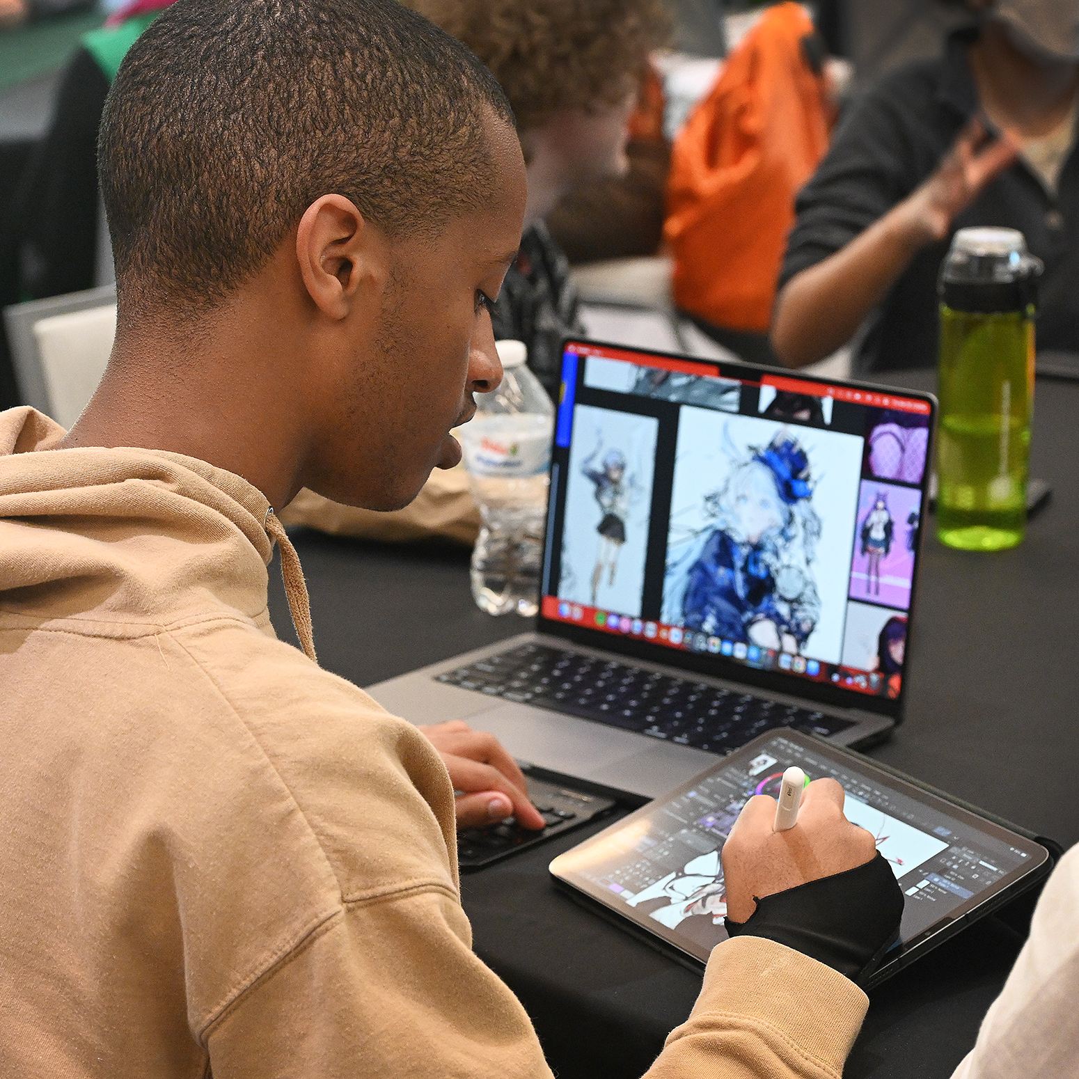 Creative Students, Alums Come Together to Connect. Person with a brown hoodie holds a stylus on a tablet.