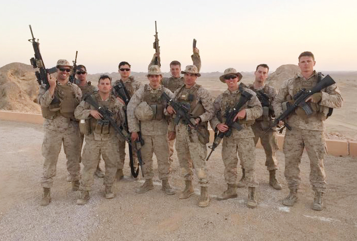 Group photo of marines in uniform with the desert in the background.